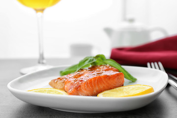Fish fillet served with lemon slices and fresh basil leaves on kitchen table