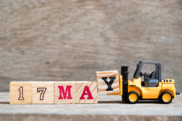 Toy forklift hold block Y to complete word 17 may on wood background (Concept for calendar date for month May)