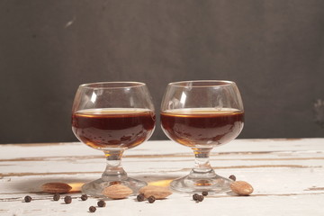 Two glass of brandy on white aged wood background.