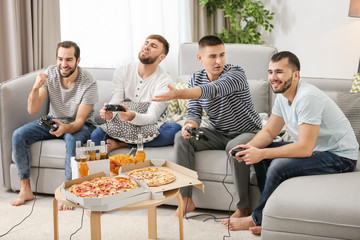 Young men playing video games at home