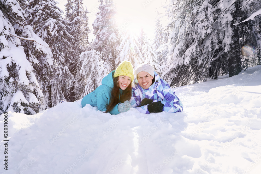 Sticker Happy couple lying on snow in countryside. Winter vacation