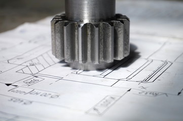 A new piece of gear after making the teeth lies on the drawing in the workshop in production