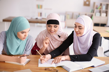 Muslim women in traditional clothes studying indoors