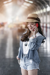 young beautiful woman is standing and using a smartphone while waiting for a train