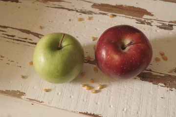 Red and green apple on aged, old white wood background.