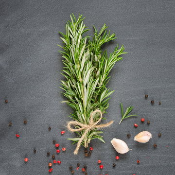 Bunch of rosemary with garlic and spices on chalk board