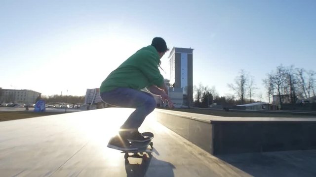 Handsome man jumping on the ramp at the city street in sunset