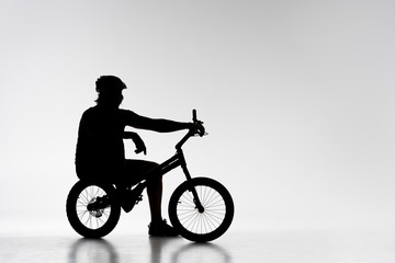 Fototapeta na wymiar silhouette of trial biker relaxing on bicycle on white