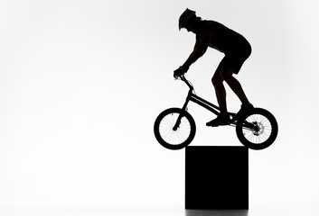 Fototapeta na wymiar silhouette of trial cyclist balancing on cube on white