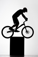 Fototapeta na wymiar silhouette of trial cyclist balancing on stand on white
