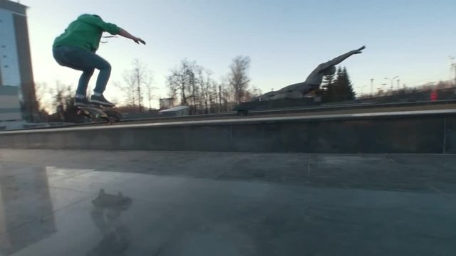 Skateboarder does extreme tricks on the ramp outdoors in sunset