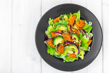 Delicious salad with avocado, pumpkin, greens