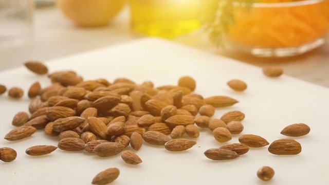 Slow motion of rosted almonds falling on white kitchen board
