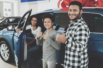 African american family at car dealership. Father, mother and son standing near new car.