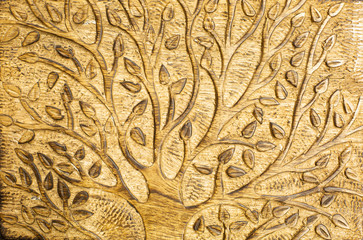 A rustic wood carving of a tree with leaves using natural pale colored wood and showing chisel marks between the branches