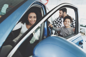 African american family at car dealership. Father, mother and son inspect new car.