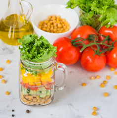 Salad in a jar. Homemade healthy salad from chickpea, tomato, yellow paprika, cucumber and green lettuce