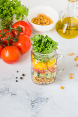Salad in a jar. Homemade healthy salad from chickpea, tomato, yellow paprika, cucumber and green lettuce