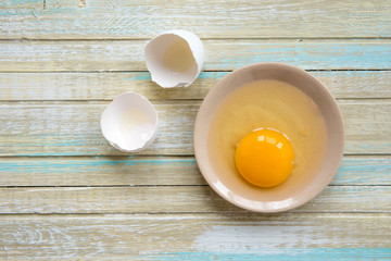 Egg on a wooden background, raw yolk in a plate top view