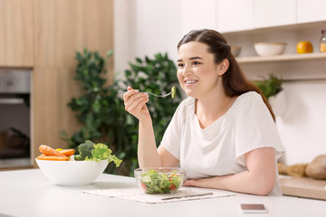 Obraz na płótnie Canvas Favorite food. Joyful gay woman smiling and eating salad