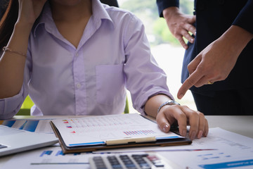 Female subordinate receiving reprimand from boss for being too late at meeting. Pointing on...