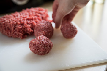Frau bei Zubereitung von Hackbällchen aus Schwein und Rind in Küche