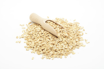 Copos de avena en grano en una cuchara de madera sobre fondo blanco