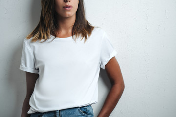 Woman in white blank t-shirt, grunge wall, studio close-up