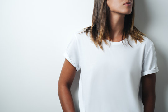 Woman in white blank t-shirt, empty wall, studio close-up