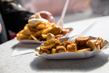 Mann isst Currywurst Pommes Mayo draußen am Wochenmarkt Imbiss