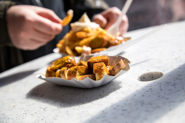 Mann isst in gemeinsamer Mittagspause Currywurst Pommes Mayo