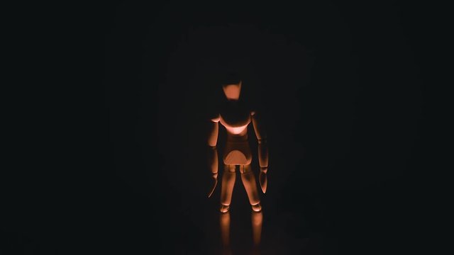 wooden man on black background with backlight from below