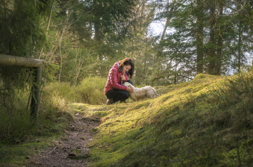 Naklejka na ściany i meble Woman caressing her dog in a fir forest