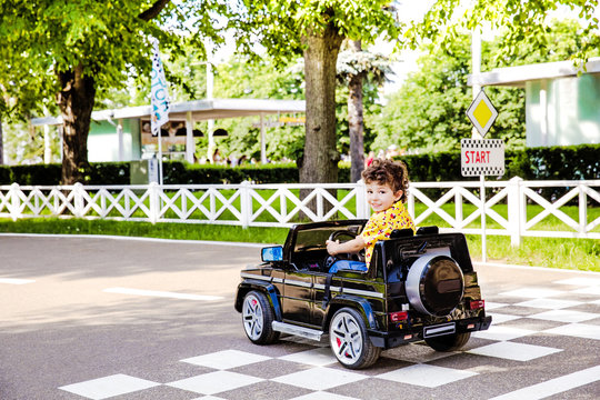 Amusement Park, a funny boy rides on a toy electric car on a sunny summer day, finish marking