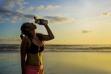 thirsty beautiful Asian sport runner woman drinking water in front of the sea after running workout...