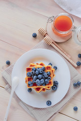 Belgian waffles with blueberries on the light wooden table. Healthy breakfast. 