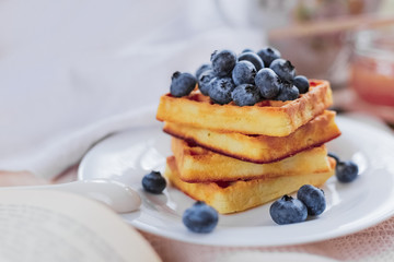 Belgian waffles with blueberries on the light wooden table. Healthy breakfast. 