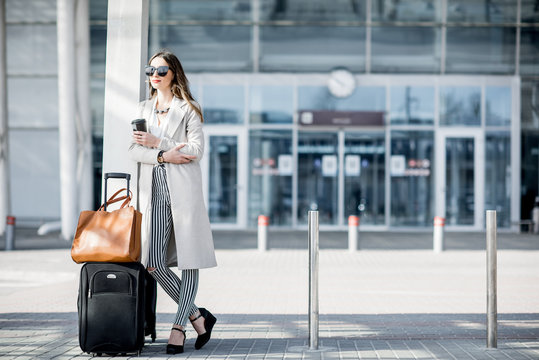 Business woman standing near the airport with luggage during the business trip