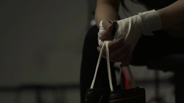 Woman at the boxing club sitting and holding gloves