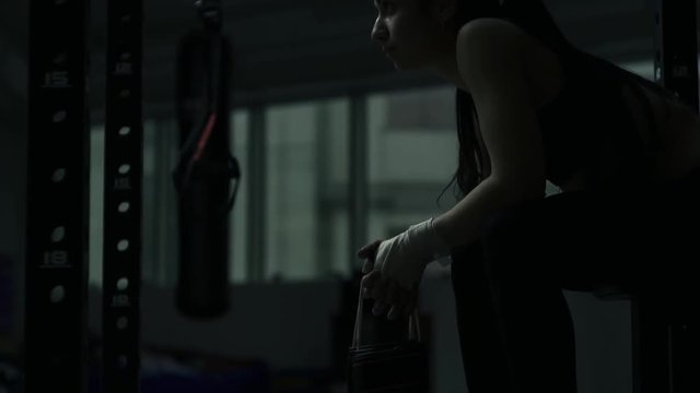 Woman at the boxing club sitting and holding gloves