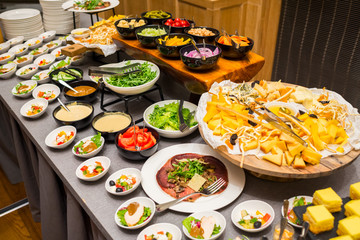 banquet table with salads and cheese assortment and vegetables cut into plates