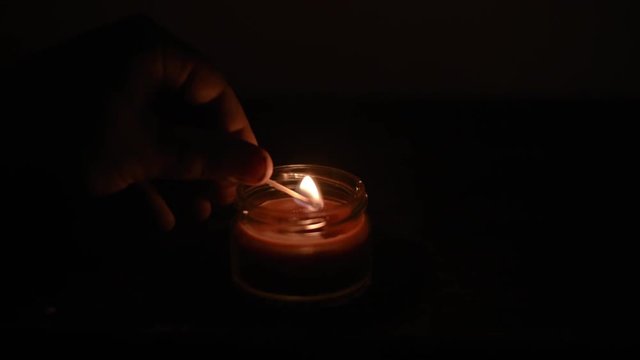 a burning candle in a dark room