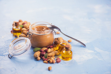 Natural peanut butter with oil in a glass jar and peanuts