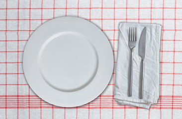 Leerer Teller und Besteck auf rot weißem Küchentuch