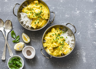 Salmon curry and rice in curry dishes on grey background, top view. Indian cusine style. Flat lay