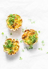 Mini savory pie with chicken, leek, cheese on light background, top view. Delicious appetizer, snack, breakfast, tapas