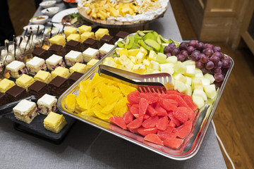 sweet fruit slices, watermelon, melon, grapes, kiwi, banana and candied fruits spread out on a metal tray