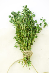 Bunch of fresh thyme leaves tied with string on white background. Selective focus