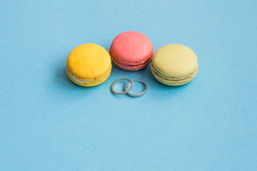 Wedding rings near macaroons on blue background. Bright and color concept. Copyplace, place for text. .