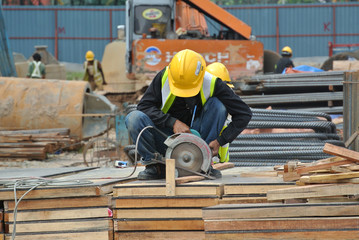 Carpenter using electrical powered circular saw to cut wood at the construction site in Malacca, Malaysia. 